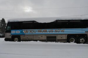 bus recouvert de neige et avec un tag "CAN YOU HEAR US NOW" tagué en rouge sur sa longueur