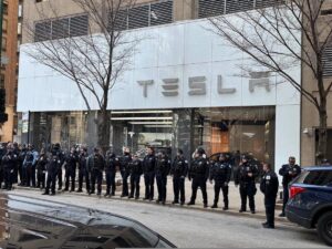 rangée de très nombreux flics devant un concessionnaire tesla, au passage d'une manifestation du 8 mars